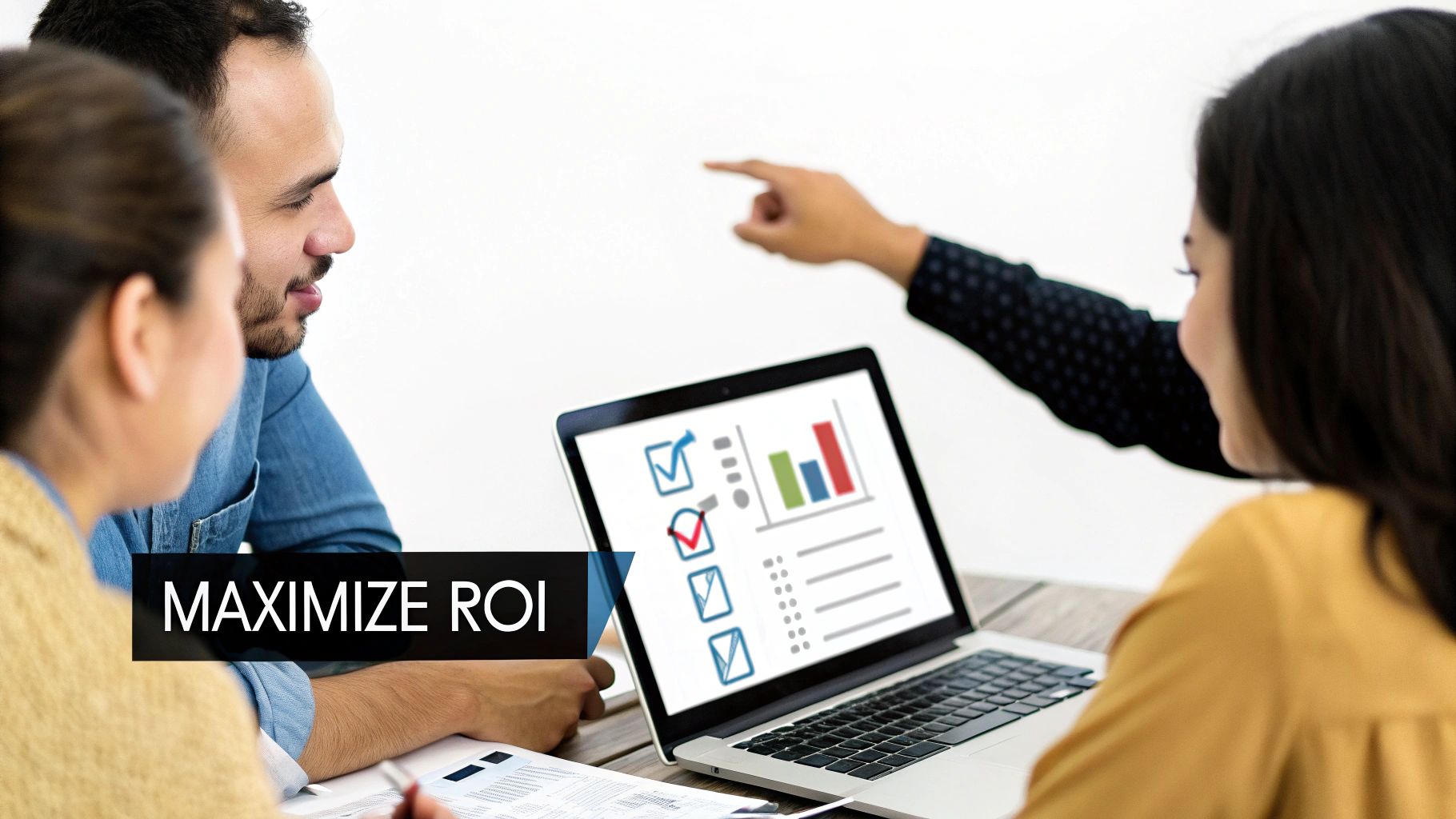 Three professionals discuss data on a laptop, aiming to maximize ROI during a business meeting.