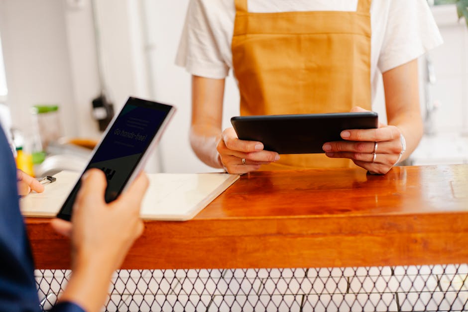 Image of a barista using a digital tablet at a coffee shop, surrounded by coffee equipment