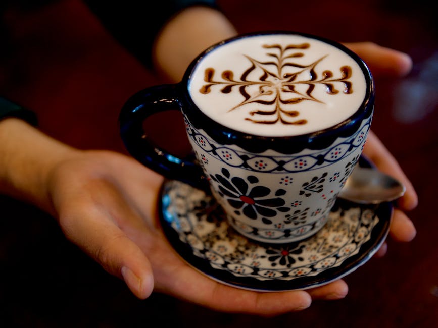 A barista smiling while serving specialty coffee in an inviting café setting, showcasing unique coffee blends and artfully crafted drinks.