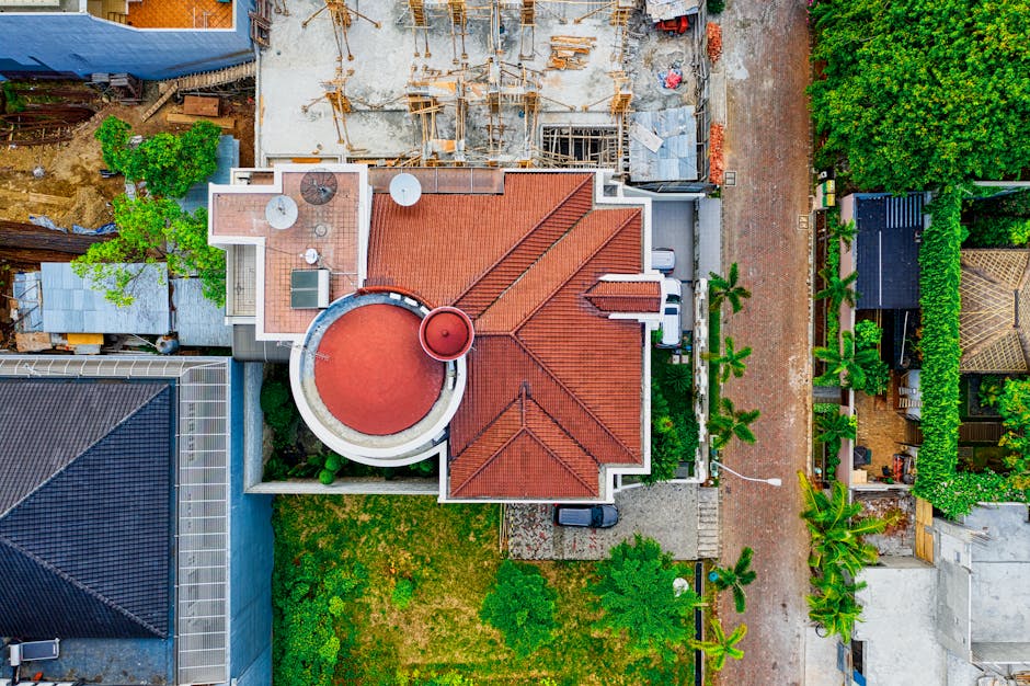 A thriving green roof on a modern building surrounded by greenery and cityscape.