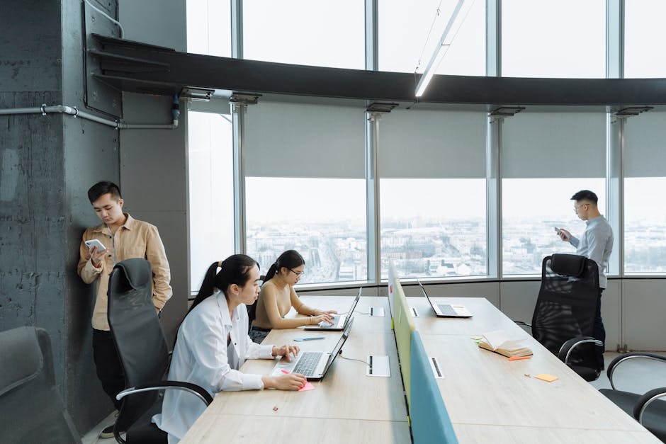 A vibrant office environment showcasing employees using various digital communication tools like tablets, laptops, and smartphones.
