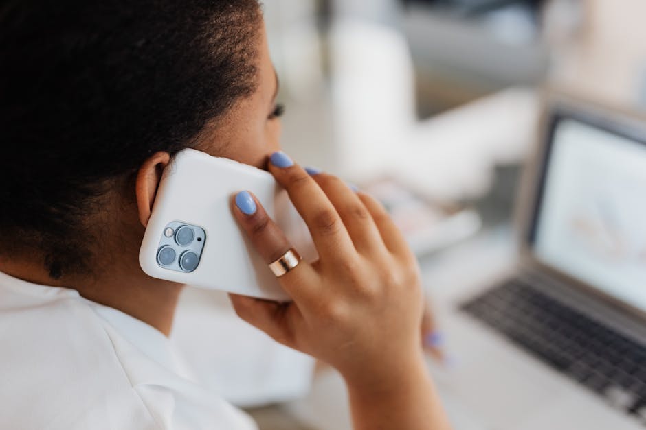 A close-up of two people on a phone call in a lively office environment, engaged in a friendly conversation.