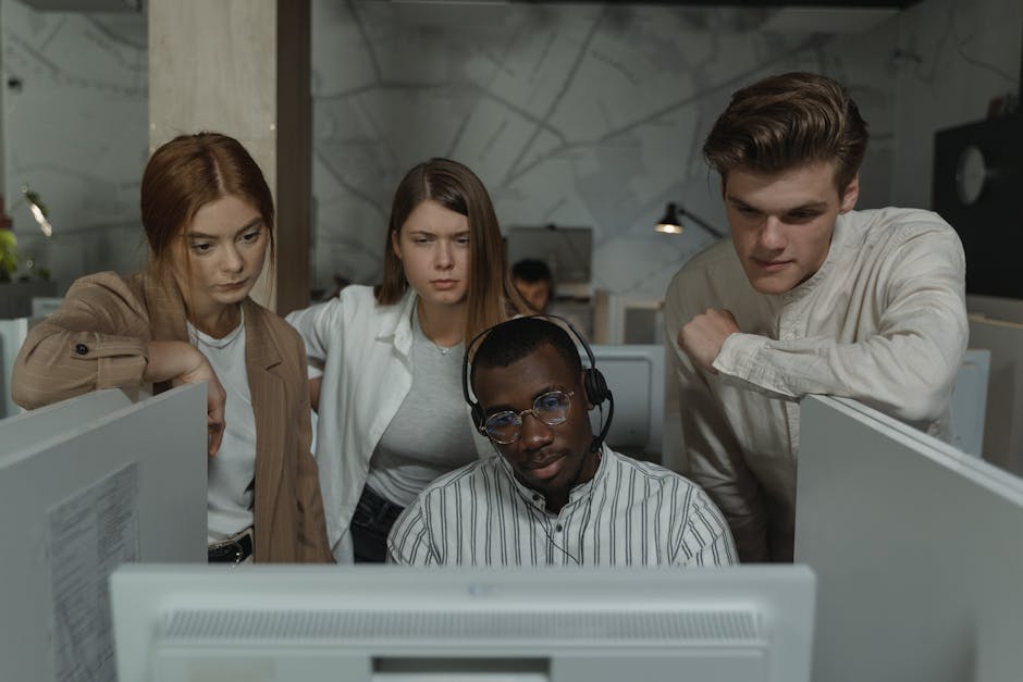 A group of business professionals engaged in a discussion over a phone call, with one person looking at a computer screen displaying call management software.