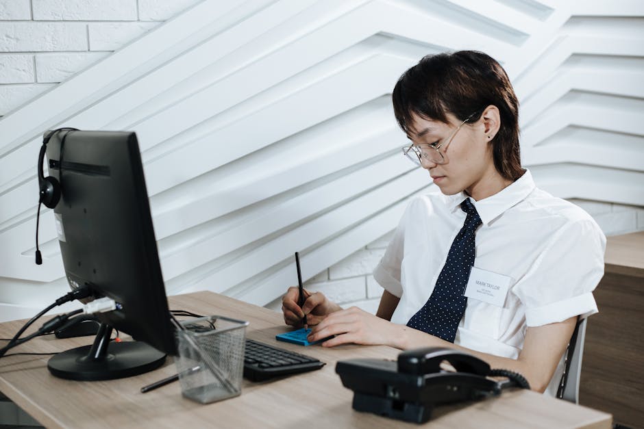 A focused phone agent engaged in a call, with computer repair tools and customer inquiries in the background.