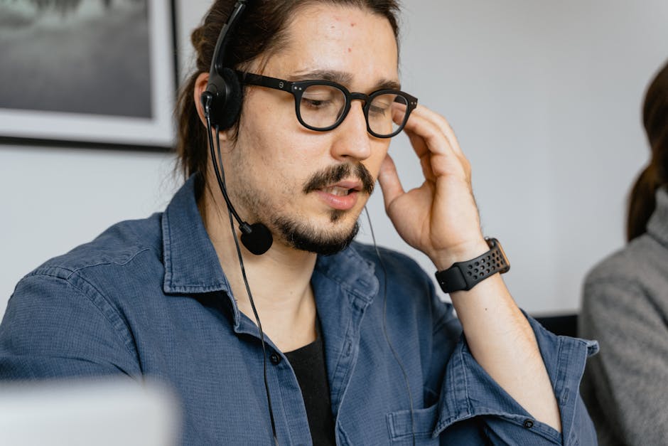 A close-up shot of a focused phone agent working at a desk, talking with clients while taking notes.