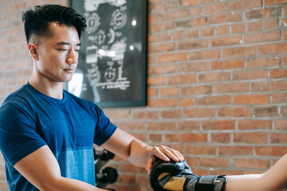 A personal trainer on a phone call, engaging with a client, with fitness equipment in the background.