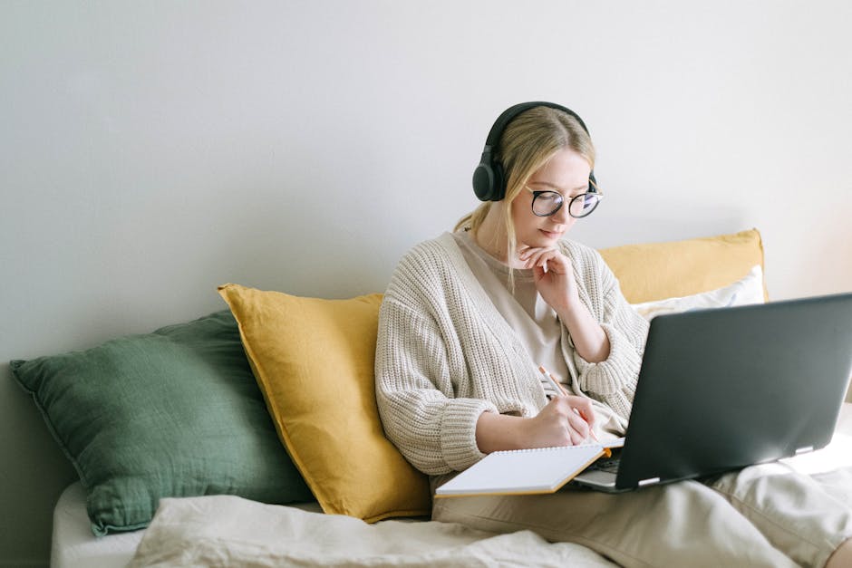 A business professional listening to recorded calls, taking notes while analyzing lead data on a laptop in a modern office.