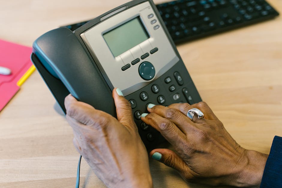 A business professional speaking on a landline phone in a sleek office environment.