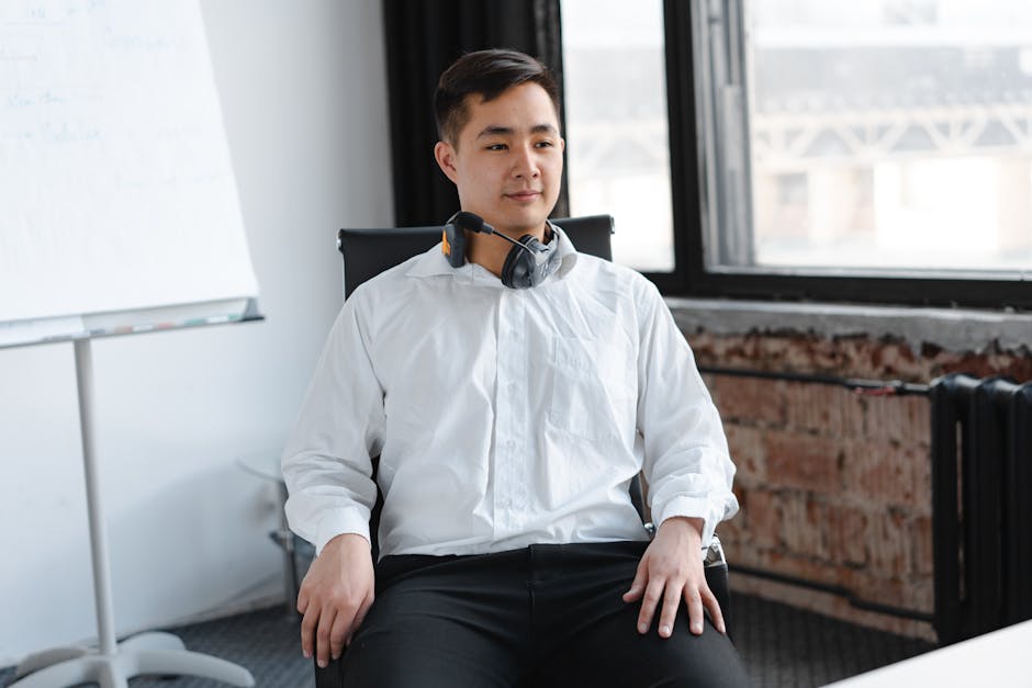 A friendly phone agent engaged in conversation with a customer, using a headset in a bright office setting.