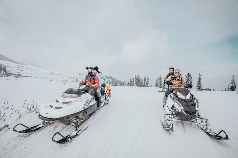 A scenic winter landscape showing a snowmobile tour group enjoying a ride through a snowy forest.