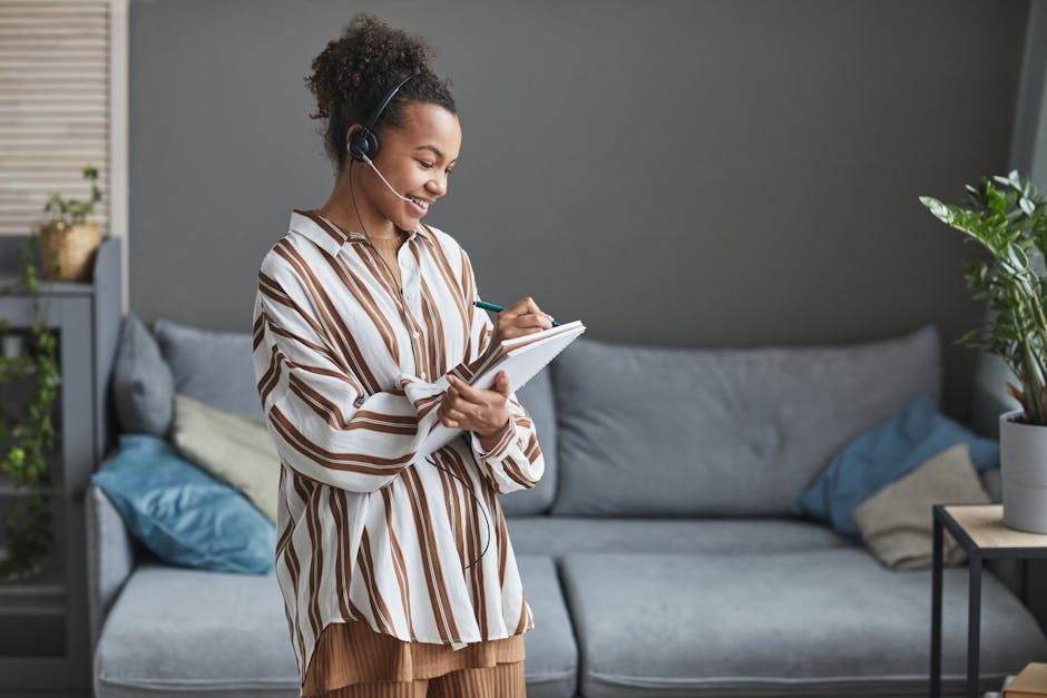 A team member on the phone, wearing a headset and smiling warmly while taking a call at a stylish hair salon reception area.