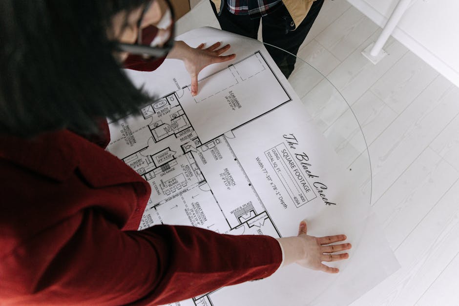 A professional construction phone agent speaking with a prospective client over the phone, with construction plans in the foreground.