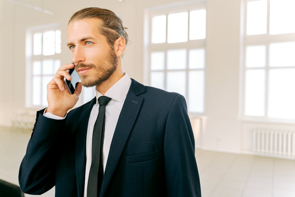 A stylish business professional using a Bluetooth headset while making a phone call in a modern office setting.
