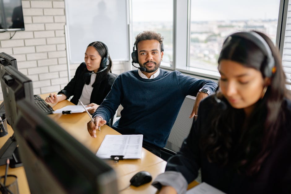 A modern office setting with employees collaborating over video calls, showcasing VoIP technology in action