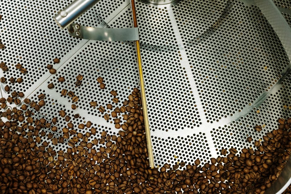 An artisan coffee roaster delicately measuring freshly roasted coffee beans surrounded by colorful coffee bags and brewing equipment.